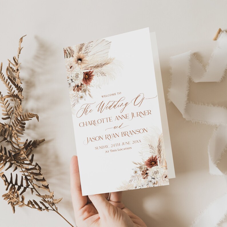 May include: A wedding ceremony order of service with a white background and a floral design featuring dried pampas grass, white and red flowers. The text reads "Welcome to The Wedding of Charlotte Anne Jurner and Jason Ryan Branson, Sunday, 24th June 20XX, At This Location."