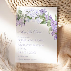 May include: A white rectangular wedding save the date card featuring a watercolor illustration of purple and light blue lilac flowers at the top. The text reads Save The Date, FOR THE WEDDING OF SOPHIE ANNE JURNER and DAVID RYAN BRANSON, Saturday 08 | 10 | 20XX, AT THIS LOCATION, Formal invitation to follow.