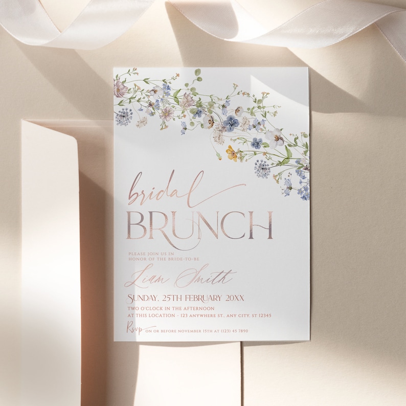 May include: A white bridal brunch invitation with a floral border. The text reads "bridal brunch" in a rose gold font. The invitation is for Liam Smith and is for Sunday, 25th February 20XX at 2:00 PM. The RSVP date is 15th November.