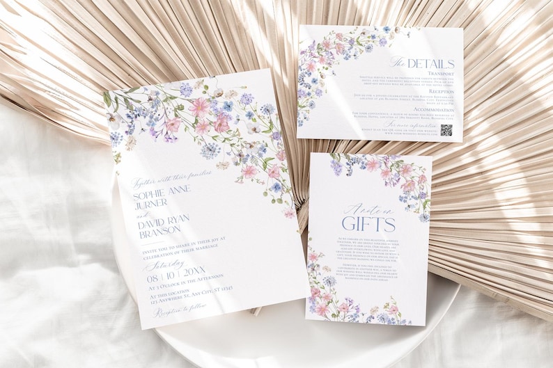 K&ouml;nnte beinhalten: Ein Set aus drei wei&szlig;en Hochzeitseinladungskarten mit zarten Aquarellillustrationen von rosa und blauen Wildblumen. Der Text enth&auml;lt die Namen Sophie Anne Jurner und David Ryan Branson sowie Abschnitte f&uuml;r Details und Geschenke.