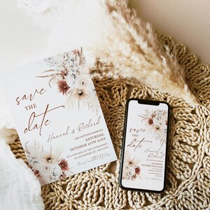 May include: Save the date card with a floral design in shades of brown, white, and cream. The card features the text "Save the Date" in a handwritten font and the names "Hannah & Richard". The date is October 25th, 20XX.