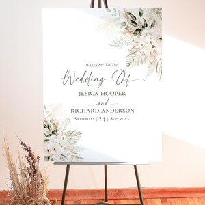 May include: A white wedding welcome sign on a black easel featuring floral arrangements in the top right and bottom left corners. The text reads: Welcome To The Wedding Of JESICA HOOPER and RICHARD ANDERSON SATURDAY | 24 | SEP, 20XX.