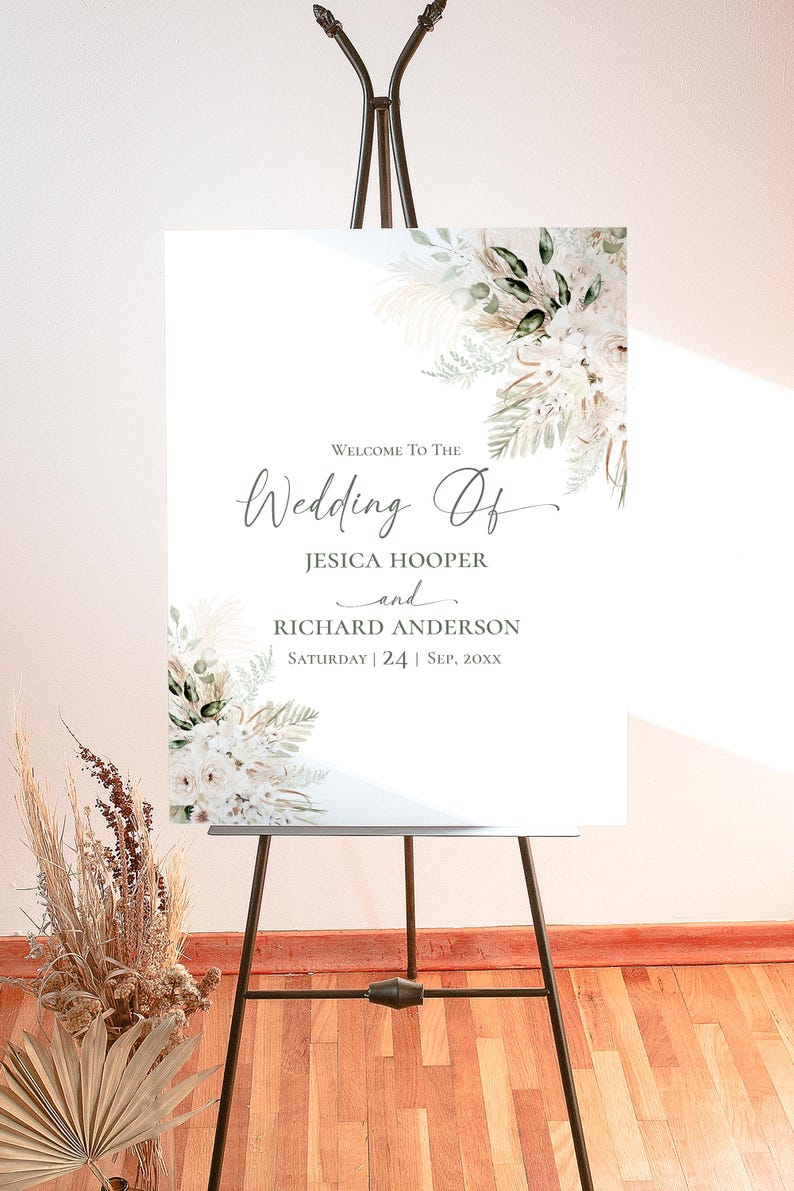 May include: A white wedding welcome sign on a black easel featuring floral arrangements in the top right and bottom left corners. The text reads: Welcome To The Wedding Of JESICA HOOPER and RICHARD ANDERSON SATURDAY | 24 | SEP, 20XX.