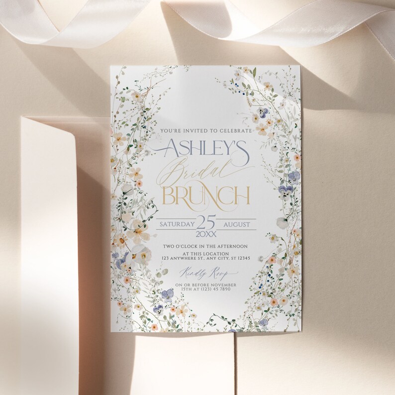 May include: A floral bridal brunch invitation with a white background and a wreath of watercolor flowers. The text reads "You're invited to celebrate Ashley's Bridal Brunch, Saturday 25 August 20XX, Two o'clock in the afternoon at this location: 123 Anywhere St. Any City, ST 12345, RSVP on or before November 15th at (123) 45 7890."