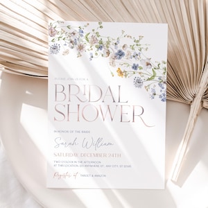 May include: A white rectangular bridal shower invitation card featuring a floral garland of blue, purple, and yellow wildflowers at the top. The text reads: PLEASE JOIN US FOR A BRIDAL SHOWER IN HONOR OF THE BRIDE Sarah William SATURDAY, DECEMBER 24TH.