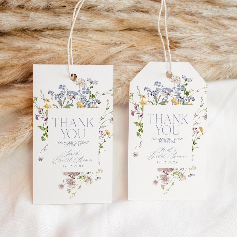 May include: Two white thank you tags with a floral design featuring blue and yellow flowers. The text on the tags reads "Thank You for making today so special!" and includes the text "Sarah's Bridal Shower 12.12.20XX".