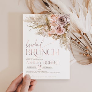 May include: A white bridal brunch invitation with a pink and brown floral design. The text reads "bridal brunch" in a pink script font. The invitation includes the bride-to-be's name, the date, and the time of the event. RSVP information is also included.