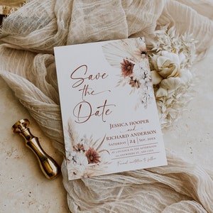 May include: A white Save the Date card featuring floral illustrations in shades of burgundy and beige. The text reads: Save the Date, Jessica Hooper and Richard Anderson, Saturday 24 Sep, 20xx, at 3 o'clock in the afternoon, 123 Anywhere St., Any City, Formal invitation to follow.