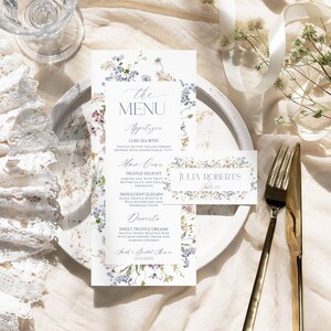 Puede incluir: Una tarjeta de men&uacute; vertical y una tarjeta de sitio rectangular con un delicado borde floral de flores silvestres azules, rosas y verdes. El men&uacute; enumera platos como Luxe Sea Bites y Truffle Delight, mientras que la tarjeta muestra el nombre Julia Roberts.