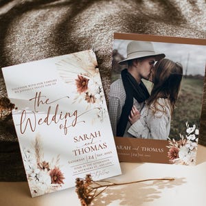 May include: Two rectangular wedding invitation cards featuring a photograph of a couple kissing, dried floral illustrations in shades of brown and cream, and printed text including the names Sarah and Thomas and the date September 24, 20XX.