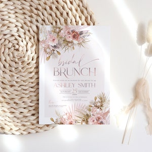 May include: A blush pink and gold bridal brunch invitation with a floral design. The text reads "bridal brunch" and "Please join us in honor of the bride-to-be Ashley Smith, Saturday 25 December 20xx, Two o'clock in the afternoon at this location 123 Anywhere St, Any City, ST 12345".