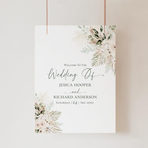 May include: A rectangular wedding welcome sign featuring floral arrangements of pampas grass and greenery in the top right and bottom left corners. The text reads: Welcome To The Wedding Of JESICA HOOPER and RICHARD ANDERSON SATURDAY | 24 | SEP, 20XX.