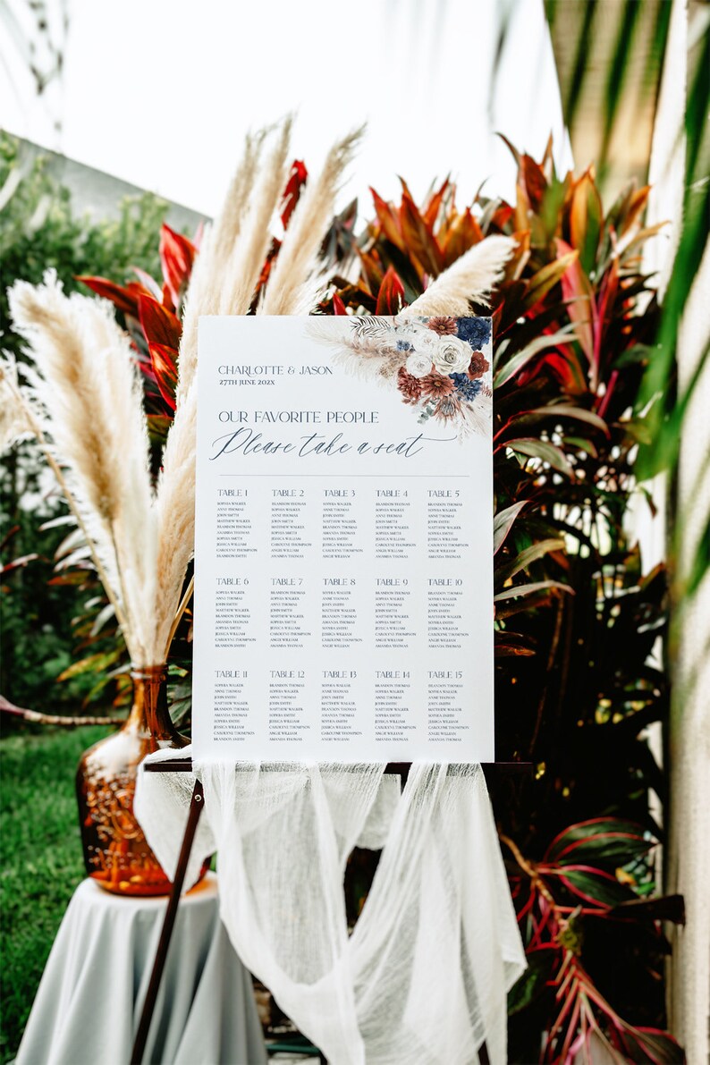 May include: A white wedding seating chart with a floral design in shades of blue, red, and white. The chart lists tables 1 through 15 with guest names. The text reads "Charlotte & Jason 27th June 20XX Our Favorite People Please Take a Seat."