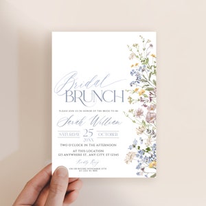 May include: A bridal brunch invitation featuring a watercolour floral design in shades of blue, yellow, and pink. The invitation includes the text "Bridal Brunch" in a blue script font and the bride-to-be's name, "Sarah William", in a cursive font. The date is Saturday, 25th October 20XX, and the time is two o'clock in the afternoon. The location is 123 Anywhere St., Any City, ST 12345. RSVP details are provided at the bottom of the invitation.