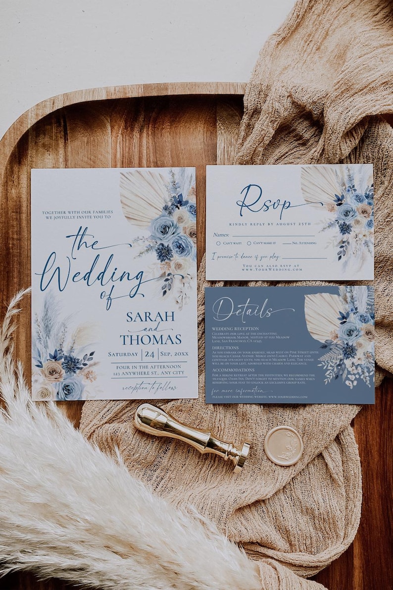 May include: Wedding invitation suite with a blue and beige color scheme. The invitation features a floral design with pampas grass and the text "The Wedding of Sarah and Thomas". The RSVP card has a blue and beige floral design with the text "RSVP" and "Kindly Reply by August 25th". The details card has a blue and beige floral design with the text "Details" and information about the wedding reception, directions, accommodations, and more.