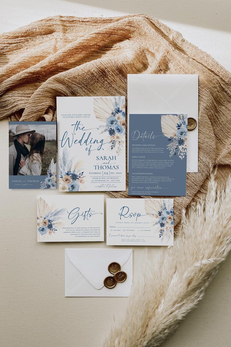 May include: A wedding invitation suite with a blue and beige color scheme. The invitation features a floral design with pampas grass and the text "The Wedding of Sarah and Thomas". The details card includes information about the wedding reception, directions, and accommodations. The RSVP card has a space for guests to provide their names and indicate whether they will be attending. The gifts card includes a message about the couple's registry.
