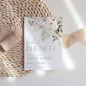Może przedstawiać: Biało-zielone zaproszenie na brunch ślubny z tekstem "bridal brunch" w szarym, ozdobnym pismie. Zaproszenie zawiera imię panny młodej, "Sophie Robert", datę "sobota, 25 grudnia 20xx" oraz godzinę i miejsce wydarzenia.