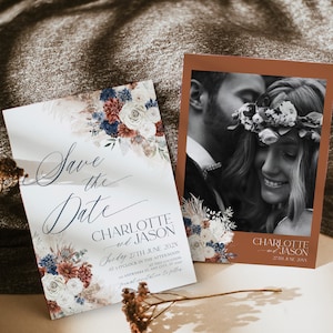 Może przedstawiać: Dwie prostokątne karty Save the Date z ilustracjami kwiatowymi w kolorze granatowym, rdzawym i kremowym. Jedna karta zawiera tekst Save the Date, Charlotte and Jason, Sunday 27th June 202X. Druga karta przedstawia czarno-białe zdjęcie pary.