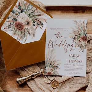 K&ouml;nnte beinhalten: Eine Hochzeitseinladung mit einem floralen Design aus getrocknetem Pampasgras und Bl&uuml;ten in Blush-T&ouml;nen. Die Einladung lautet: "Gemeinsam mit unseren Familien laden wir Sie herzlich zur Hochzeit von Sarah und Thomas ein, Samstag, 24. September 20XX, 16:00 Uhr, 21 Anywhere St, Any City, Empfang im Anschluss."