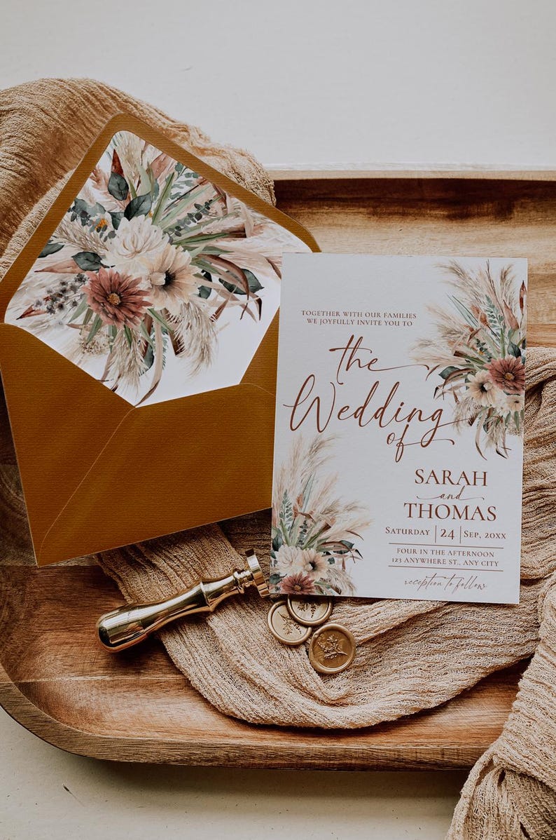 K&ouml;nnte beinhalten: Eine Hochzeitseinladung mit einem floralen Design aus getrocknetem Pampasgras und Bl&uuml;ten in Blush-T&ouml;nen. Die Einladung lautet: "Gemeinsam mit unseren Familien laden wir Sie herzlich zur Hochzeit von Sarah und Thomas ein, Samstag, 24. September 20XX, 16:00 Uhr, 21 Anywhere St, Any City, Empfang im Anschluss."