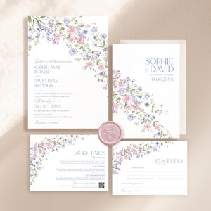 K&ouml;nnte beinhalten: Ein Hochzeitseinladungs-Set bestehend aus wei&szlig;en Papierkarten mit Aquarell-Blumenillustrationen in Rosa, Blau und Gr&uuml;n. Das Set enth&auml;lt eine Haupteinladung, eine Detailkarte und eine Antwortkarte, akzentuiert durch ein rundes, hellrosa Wachssiegel.