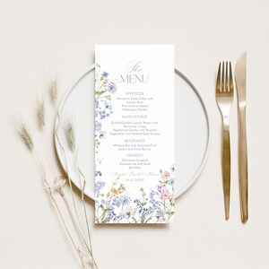 K&ouml;nnte beinhalten: Eine Hochzeitsmen&uuml;karte mit einem floralen Design mit blauen, rosa und wei&szlig;en Blumen. Das Men&uuml; umfasst Vorspeisen, Hauptgericht, Getr&auml;nke und Desserts. Der Text auf der Karte lautet "The Menu" und "14.12.20XX".