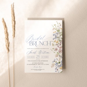 May include: A white bridal brunch invitation with blue and purple floral illustrations. The text reads "Bridal Brunch" in a blue script font. The invitation is for Sarah William on Saturday, 25th October 20XX at 2:00 PM. The RSVP deadline is 15th November.
