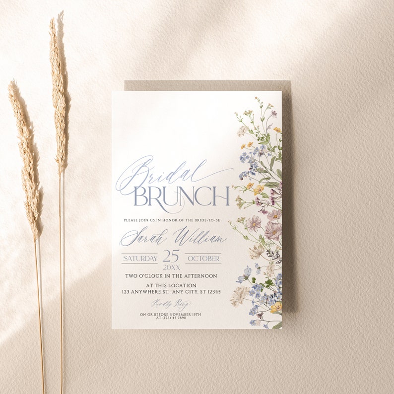 May include: A white bridal brunch invitation with blue and purple floral illustrations. The text reads "Bridal Brunch" in a blue script font. The invitation is for Sarah William on Saturday, 25th October 20XX at 2:00 PM. The RSVP deadline is 15th November.