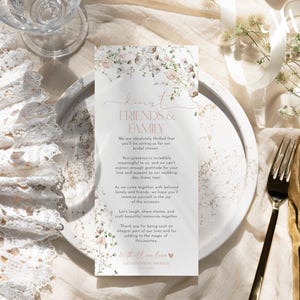 May include: A rectangular bridal shower invitation card featuring a floral border of soft pink and green watercolor flowers. The text reads: Dearest FRIENDS & FAMILY, We are absolutely thrilled that you'll be joining us for our bridal shower.