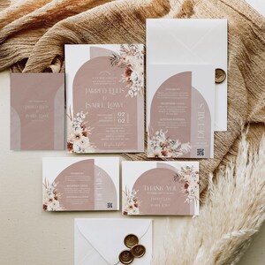 May include: A set of wedding invitations with a blush pink and white floral design. The invitations feature a modern, geometric arch with the text "Jarred Ellis & Isabel Lowe" and the date "July 02, 2023".