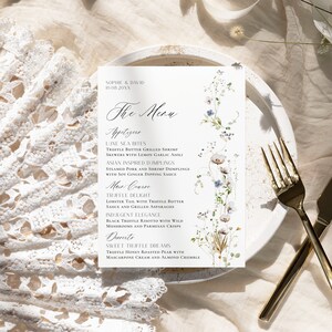 May include: A wedding menu card with a floral design. The menu includes appetizers, main course, and dessert. The appetizers are Luxe Sea Bites, Truffle Butter Grilled Shrimp Skewers with Lemon Garlic Aioli, and Asian Inspired Dumplings. The main course is Truffle Delight, Lobster Tail with Truffle Butter Sauce and Grilled Asparagus, and Indulgent Elegance, Black Truffle Risotto with Wild Mushrooms and Parmesan Crisps. The dessert is Sweet Truffle Dreams, Truffle Honey Roasted Pear with Mascarpone Cream and Almond Crumble.