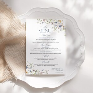 May include: A floral wedding menu with a blue and white floral design. The menu includes appetizers, main course, salad, and desserts. The text at the bottom of the menu reads "Charlotte & Jason 27th June 20XX".
