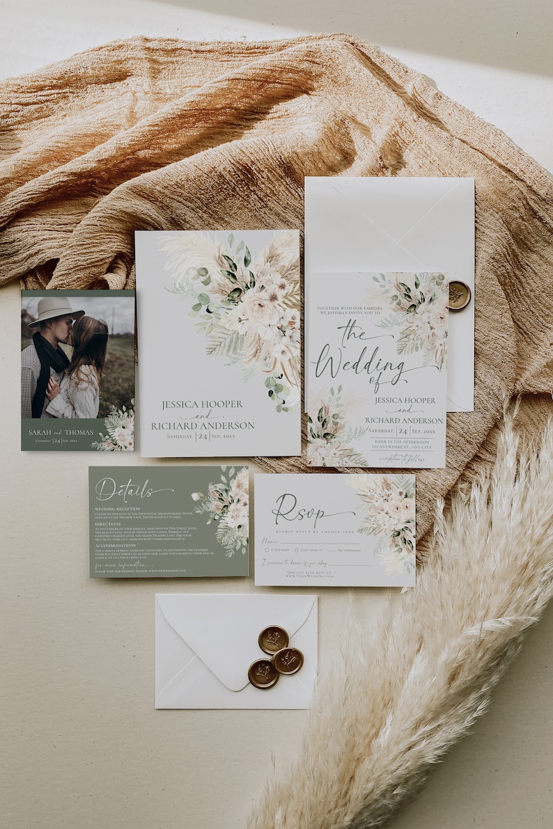 May include: A wedding stationery set featuring a photo card of a couple, an invitation, a details card, and an RSVP card. The cards are decorated with watercolor pampas grass and floral illustrations in muted green and beige tones.
