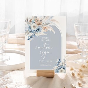 May include: A printable sign with a blue and white floral design. The sign says "Fully Editable Custom Sign 5x7" or "8x10" Create & Print Unlimited Signs.