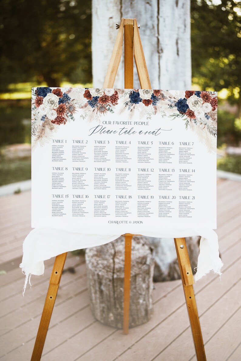 May include: A wedding seating chart with a floral design in shades of red, white, and blue. The chart lists tables 1 through 21 with guest names. The text at the top reads "Our Favorite People Please Take a Seat." The bottom of the chart reads "Charlotte & Jason."