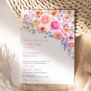 May include: A white wedding invitation card featuring a watercolor floral arrangement of pink, orange, and purple flowers at the top. The text reads: Together with their families, SOPHIE ANNE JURNER and DAVID RYAN BRANSON, INVITE YOU TO SHARE IN THEIR JOY AT CELEBRATION OF THEIR MARRIAGE, Saturday, 08 | 10 | 20XX, AT 3 O'CLOCK IN THE AFTERNOON, AT THIS LOCATION, 123 ANYWHERE ST, ANY CITY, ST 12345, Reception to follow.