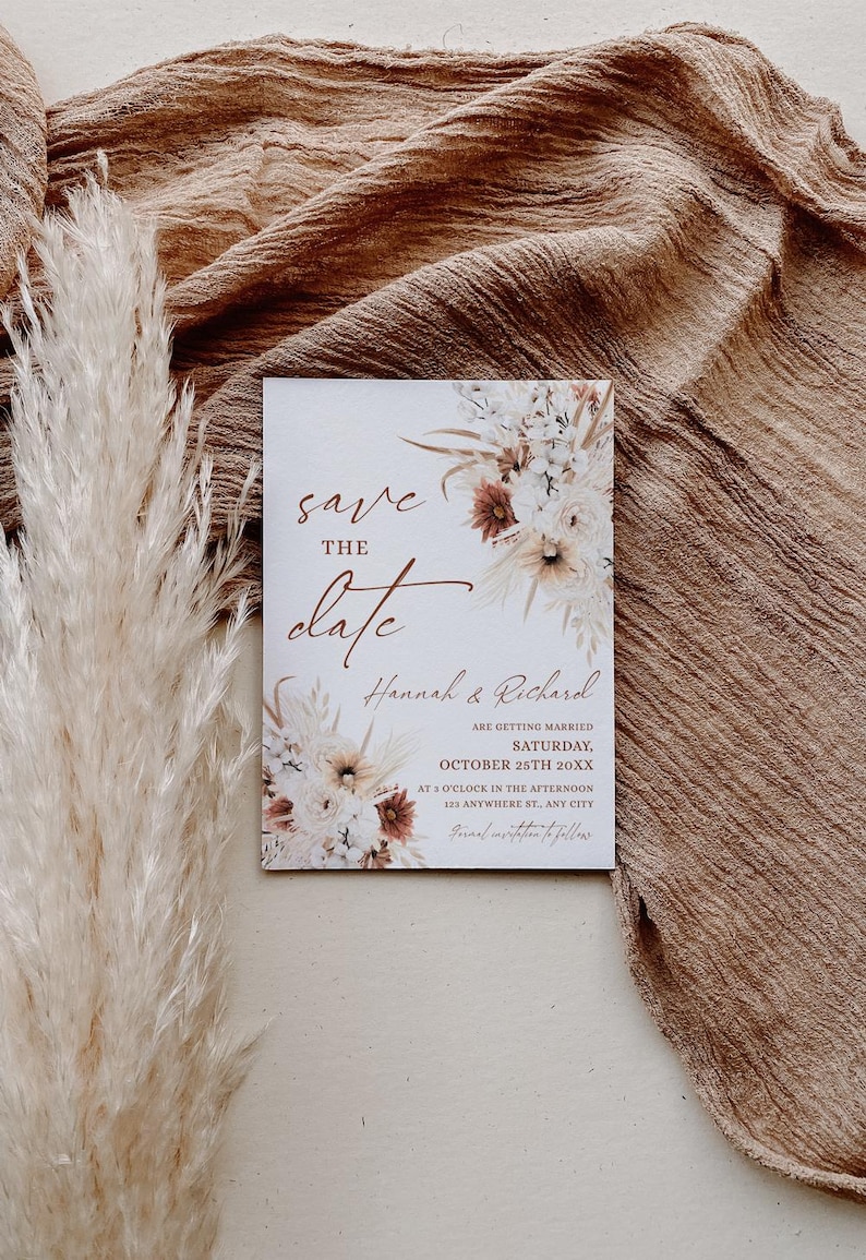 May include: Save the date wedding invitation with a floral design in shades of brown, white, and cream. The text reads "Save the Date" with the names "Hannah & Richard" and the date "October 25th 20XX".