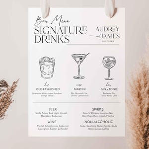 Könnte beinhalten: Ein weißes Bar-Menü-Schild mit dem Text "Bar Menu Signature Drinks" und den Namen "Audrey und James" mit einem Datum. Das Schild zeigt Illustrationen von Cocktails und listet die Getränkezutaten auf. Das Schild hängt an einem weißen Band.