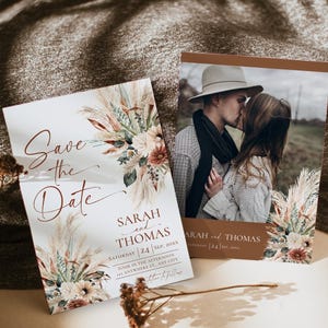 May include: Two rectangular Save the Date cards featuring a floral arrangement of pampas grass and dried flowers. One card displays the text Save the Date, Sarah and Thomas, Saturday 24 Sep, 20XX. The other card includes a photograph of a couple.