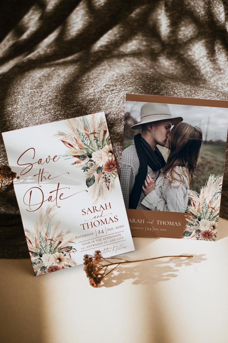 May include: Two rectangular Save the Date cards featuring a floral arrangement of pampas grass and dried flowers. One card displays the text Save the Date, Sarah and Thomas, Saturday 24 Sep, 20XX. The other card includes a photograph of a couple.