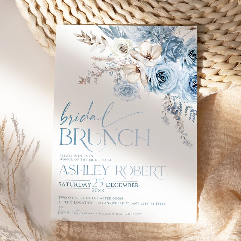 May include: A light blue and white bridal brunch invitation with a watercolor floral design. The invitation includes the text "bridal brunch", "Ashley Robert", "Saturday 25 December 20xx", "Two o'clock in the afternoon", "At this location - 123 Anywhere St., Any City, ST 12345", and "RSVP on or before November 15th at (123) 45 7890".