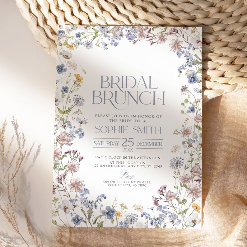 May include: A floral bridal brunch invitation with a white background and blue and purple flowers. The text reads "Bridal Brunch", "Please join us in honor of the bride-to-be Sophie Smith", "Saturday 25 December 20XX", "Two o'clock in the afternoon at this location 123 Anywhere St. Any City, ST 12345", "RSVP on or before November 15th at (123) 45 7890".