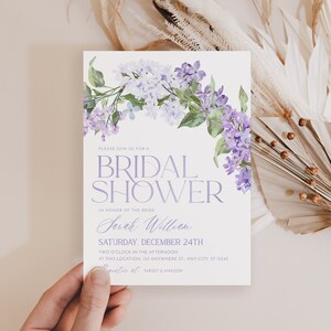 May include: A purple floral bridal shower invitation with the text 'Please join us for a Bridal Shower' in honor of the bride 'Sarah William' on Saturday, December 24th at 2 o'clock in the afternoon at 123 Anywhere St., Any City, ST 12345. The invitation also includes the text 'Register at Target & Amazon'.