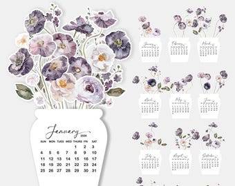 May include: A desk calendar featuring watercolor illustrations of violet poppies. The calendar includes a January 2026 page and individual month pages with floral arrangements. Available in multiple sizes: 10cm x 15cm, 14cm x 21cm, and 18cm x 27cm.