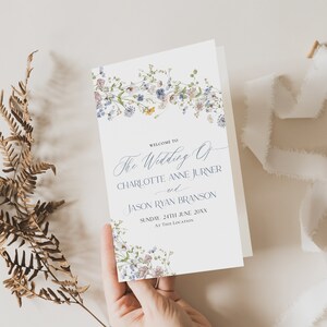 Könnte beinhalten: Ein Hochzeitsprogramm mit einem floralen Design mit blauen und weißen Blumen. Der Text lautet "Willkommen zur Hochzeit von Charlotte Anne Jurner und Jason Ryan Branson, Sonntag, 24. Juni 20XX, an diesem Ort."