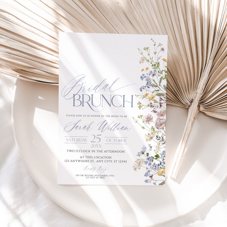 May include: A white invitation card with a floral design in shades of blue, yellow, and purple. The text on the card reads "Bridal Brunch" and includes the bride-to-be's name, "Sarah William", the date "Saturday 25 October 20XX", the time "Two O'Clock in the Afternoon", the location "123 Anywhere St., Any City, ST 12345", and the RSVP information "On or Before November 1STH at 1233 45 7890".