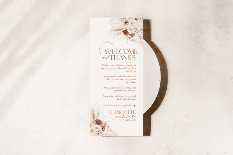 May include: A rectangular wedding thank you card featuring dried floral arrangements at the top and bottom. The text reads: Welcome and Thanks, followed by a message of gratitude, and concludes with the names Charlotte and Jason, dated 25th June 20XX.