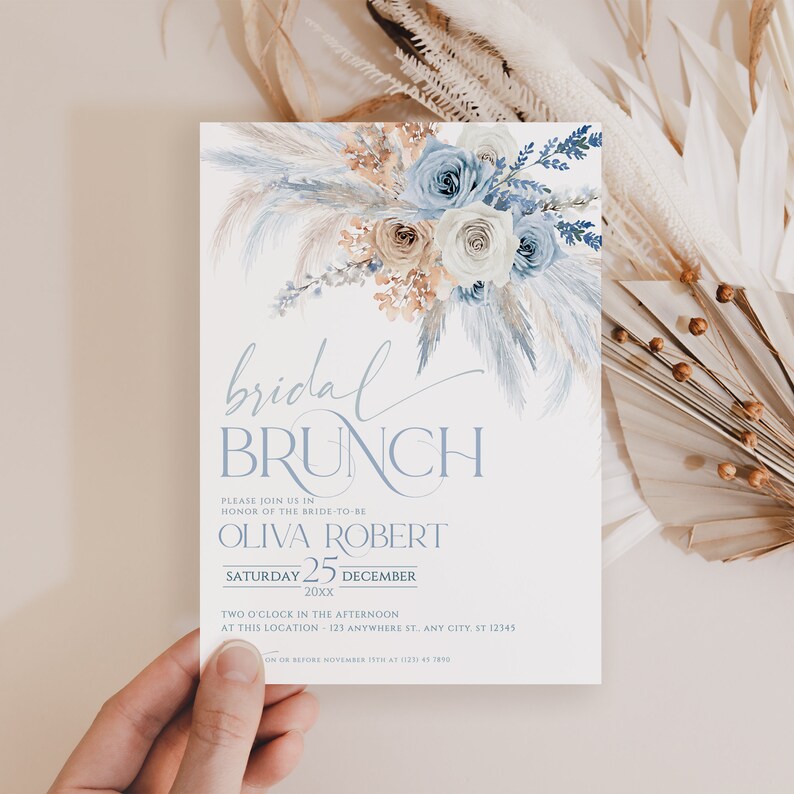 May include: A white invitation card with a watercolor illustration of blue and white flowers and pampas grass. The text reads "bridal brunch" and includes the bride-to-be's name, the date, and the time of the event.  Please join us in honor of the bride-to-be Olivia Robert, Saturday, December 25, 20xx, Two o'clock in the afternoon, at this location: 123 Anywhere St, Any City, ST 12345. RSVP on or before November 15th at 123 45 7890.
