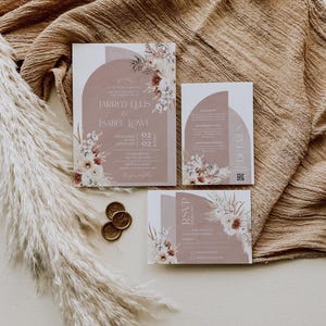 May include: Wedding invitation suite with a modern design featuring a dusty rose background with floral illustrations and a semi-circle shape. The text reads "Jarred Ellis & Isabel Lowe" and includes the date "02.02.2022".