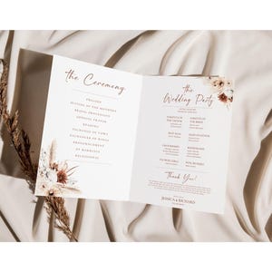 May include: A wedding ceremony program with a floral design featuring dried grasses and flowers in shades of beige, brown, and white. The program lists the order of the ceremony and the wedding party.